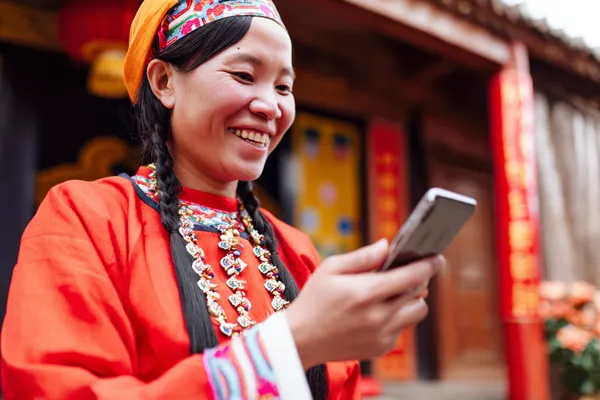 SPINARAA App — Fast, responsive, and optimized for all devices A cheerful woman in traditional clothing using her smartphone during a festive moment, showing how easily the SPINARAA app fits into everyday life.