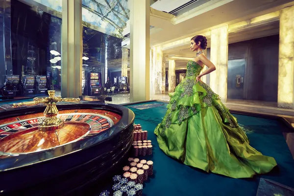 A woman in a luxurious green gown next to an ornate roulette wheel, capturing the upscale casino mood of SPINARAA.