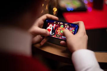 A player using their smartphone during a festive local event, representing SPINARAA’s fully mobile-friendly casino.